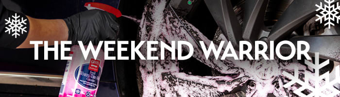 Person spraying car wheels with Wheel Cleaner, surrounded by snow foam, with the words 'The Weekend Warrior' — car care gift ideas for passionate DIY detailers from Griot's Garage.