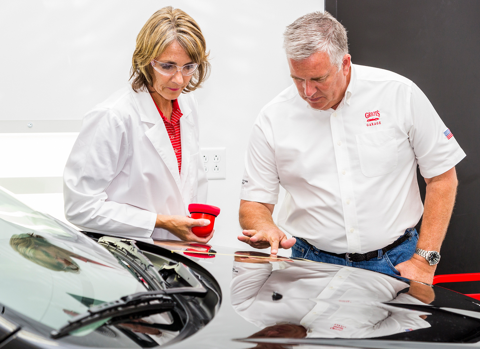 Two people inspecting wax on car hood